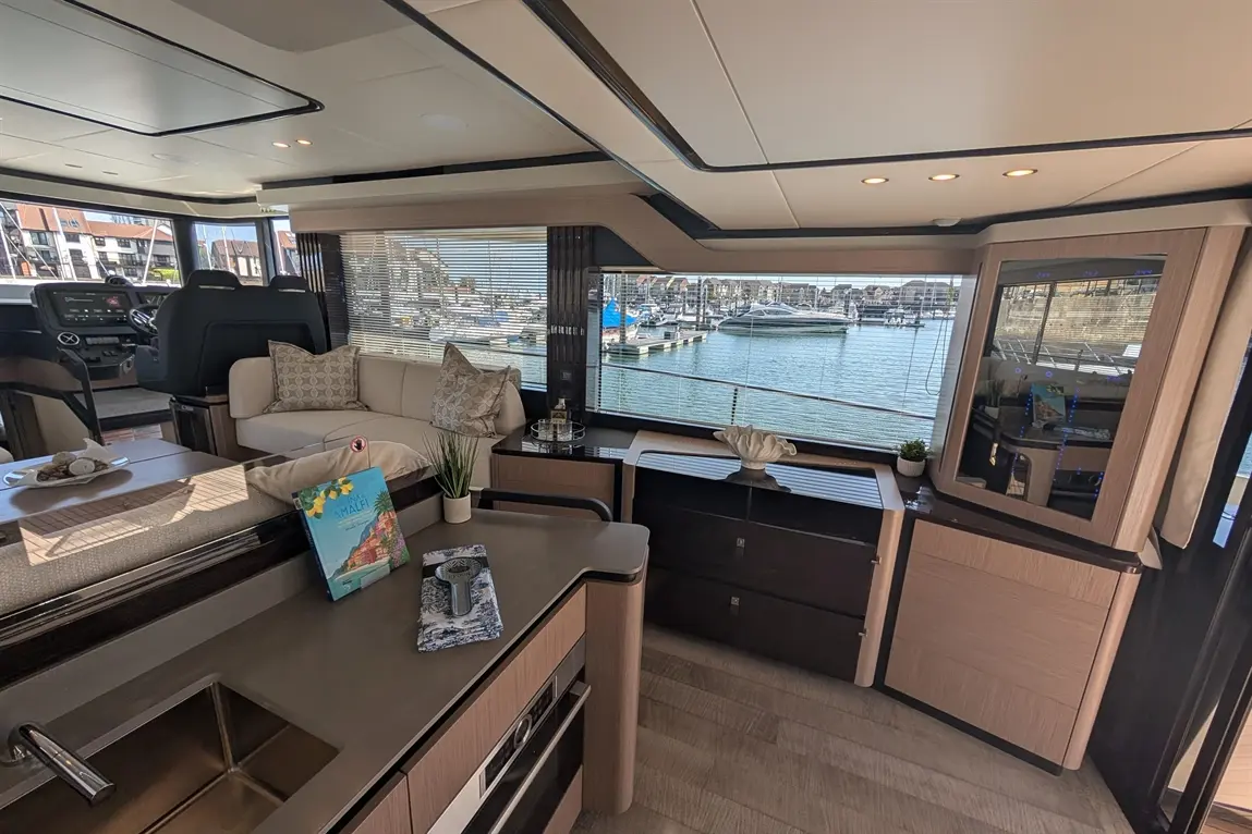 Modern boat interior featuring a sofa, kitchen area, vibrant views of the marina, and a book titled "MALTA.